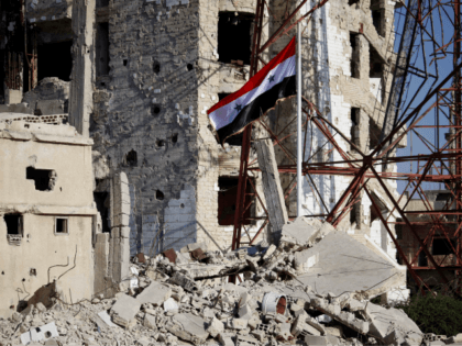 The Syrian national flag rises in the midst of damaged buildings in Daraa-al-Balad, an opposition-held part of the southern city of Daraa, on July 12, 2018. - Syria's army entered rebel-held parts of Daraa city , state media said, raising the national flag in the cradle of the uprising that …