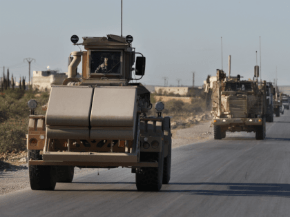 A U.S. mine detector armored vehicle, leads a convoy of U.S. troops, on a road leading to