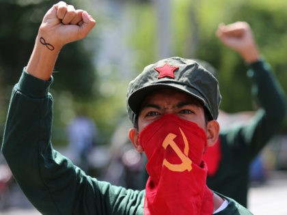 A Filipino activist uses a cloth printed with the hammer and sickle symbol to cover his fa