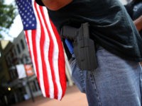 handgun-open-carry-holster-american-flag-getty CHARLOTTESVILLE, VA - AUGUST 12: A protester wearing a pistol on his hip stands near the location where a car plowed into a crowd of protestors marching through a downtown shopping district August 12, 2017 in Charlottesville, Virginia. The car allegedly plowed through a crowd, and at least one person …