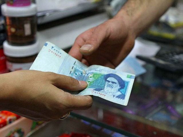 An Iranian woman pays a 20000 rial banknote (around 70 US Cent), bearing a portrait of Ira