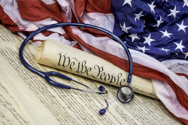 The United States Constitution rolled up on an American flag with a medical stethoscope sy