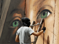 Italian artist Jorit Agoch paints a mural depicting jailed Palestinian teenager Ahed Tamimi on Israel's controversial separation barrier in the West Bank city of Bethlehem, on July 25,2018. - Tamimi, was charged earlier this year after a viral video showed her hitting two soldiers in the occupied West Bank. (Photo …