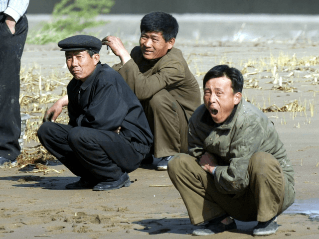 North Koreans squat on mudflats at the North Korean town of Sinuiju, opposite the Chinese