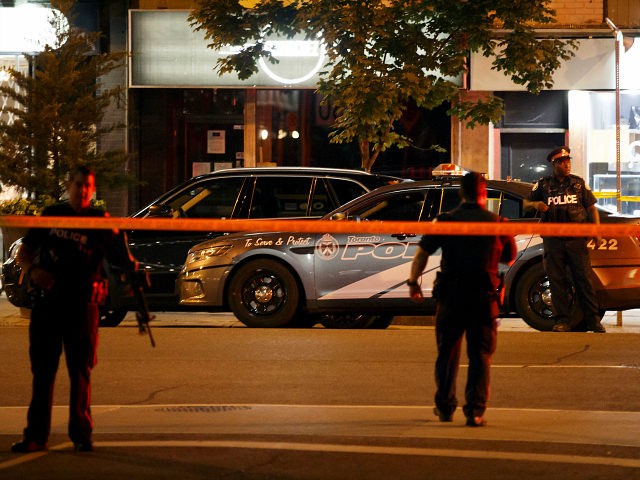 Toronto Police officers walk the scene at Danforth St. at the scene of a shooting in Toronto, Ontario, Canada on July 23, 2018. - A gunman opened fire in central Toronto on Sunday night, injuring 13 people including a child. Two dead incluiding gunman, police reported. (Photo by Cole BURSTON …