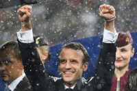 President Emmanuel Macron celebrates despite pouring rain as the France team are presented with the World Cup