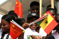 Young Senegalese wave flags to mark the arrival of President Xi on a state visit with China the west African nation's second biggest trading partner behind France, its firms having embarked on a slew of major infrastructure projects