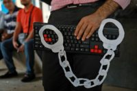 An activist holds a computer keyboard and makeshift handcuffs on July 24, 2018, during a freedom of expression protest in downtown Beirut