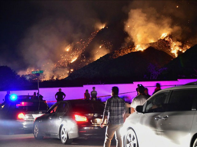 People watch flames from the Holy Fire outside Glen Ivy Hot Springs in Corona, California, southeast of Los Angeles, on August 10, 2018. - Authorities battling massive wildfires in large swathes of California issued mandatory evacuation orders and health warnings Friday over the worsening air quality as the flames grew …