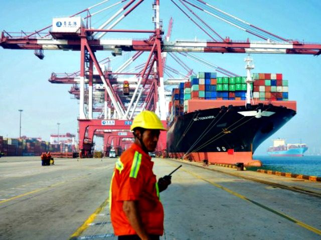 A Chinese worker looks on as a cargo ship is loaded at a port in Qingdao, Shandong Provinc