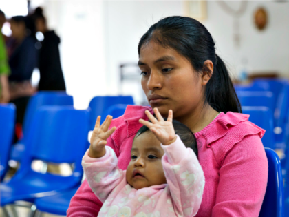 A Guatemalan woman and her infant daughter seeking asylum sit at a Catholic Charities reli