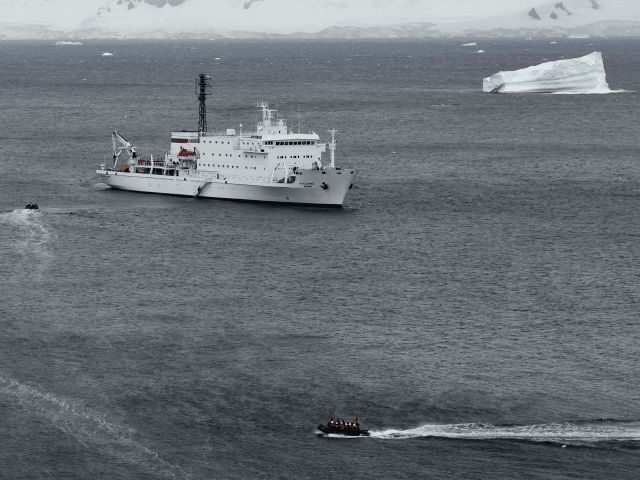 Tourist aboard zodiacs make their way to the oceanographic acoustic research vessel Akadem