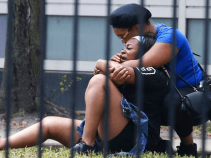 In this Sunday, Aug. 5, 2018 photo, two women cry outside the Stroger Hospital in Chicago after they were asked to leave due to overwhelming crowds of family and friends of shooting victims. Police Superintendent Eddie Johnson plans to discuss the weekend violence during a Monday news conference. (Antonio Perez/Chicago …