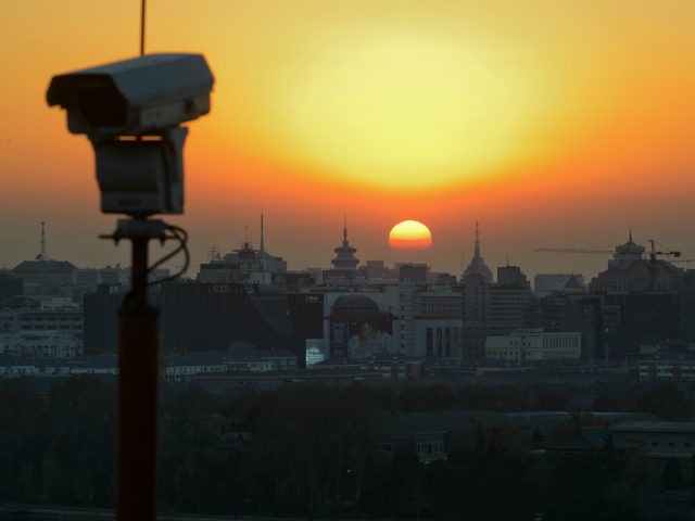 The sun sets behind the Beijing skyline and a security camera, on December 5, 2013. Beijin