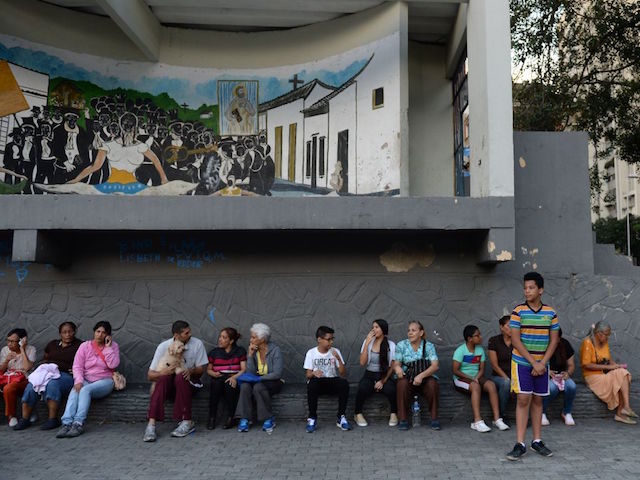 TOPSHOT - People wait in the streets after evacuating buildings in Caracas on August 21, 2