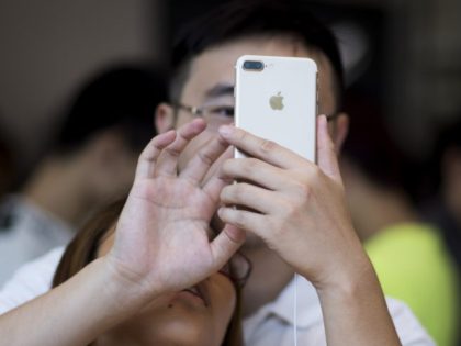 TOPSHOT - A Chinese couple tests the new iPhone 7 during the opening sale launch at an Apple store in Shanghai on September 16, 2016.