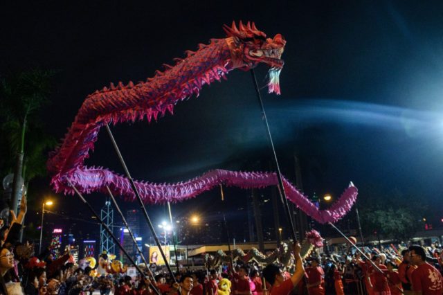 People hold a dragon and perform the dragon dance as they take part in a street parade to mark the Lunar New Year celebrations of the Year of the Rooster in Hong Kong on January 28, 2017. The Chinese New Year fell on January 28 this year and marked the …