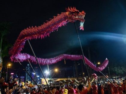 People hold a dragon and perform the dragon dance as they take part in a street parade to