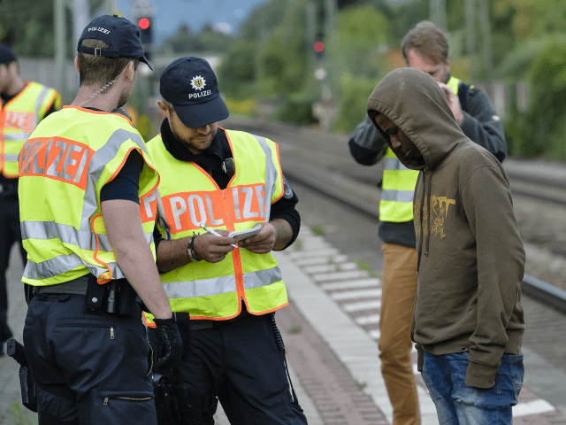 German policemen check a 16 year-old boy from Eritrea after finding him under a train trai