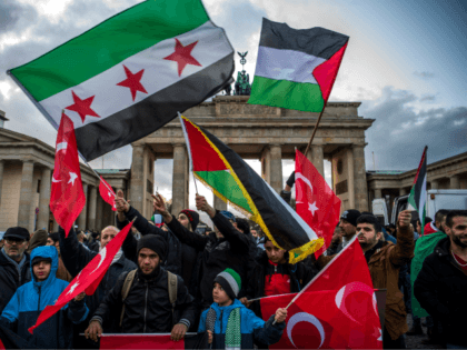 Demonstrators wave Palestinian, Turkish and Syrian flags in front of the Brandenburg Gate, next to the US embassy in Berlin on December 8, 2017, following US President Donald Trump's decision to recognise Jerusalem as the capital of the Israeli state. / AFP PHOTO / John MACDOUGALL (Photo credit should read …