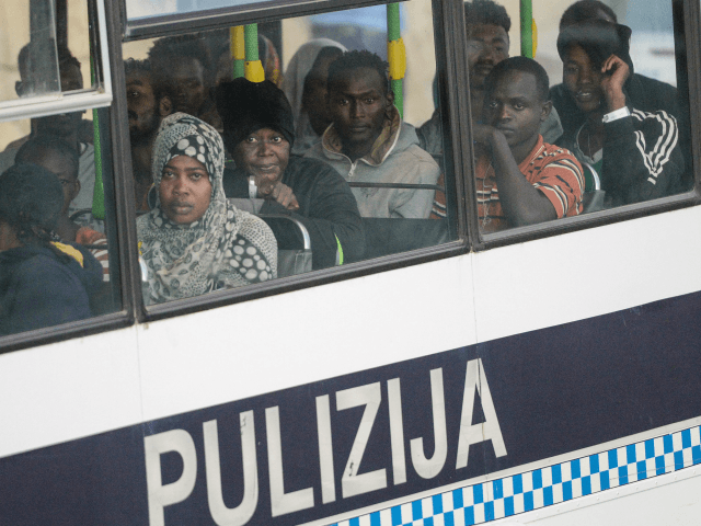 Migrants sit in a police van after they arrived aboard the 'MV Lifeline', a vessel for the German charity Mission Lifeline, in the harbour of Valletta, Malta, on June 27, 2018. - A rescue boat stranded for nearly a week in the Mediterranean with over 200 migrants docked in Malta …
