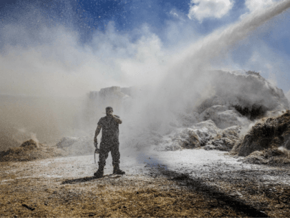 Israeli fire fighters and soldiers attempt to extinguish a fire in a kibbutz caused by a i