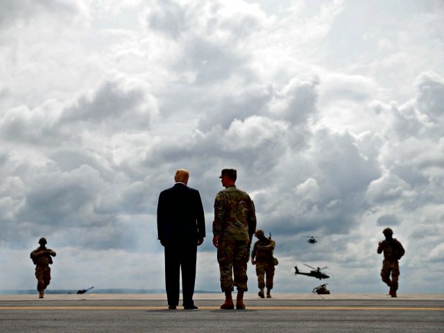 President Donald Trump talks with Maj. Gen. Walter Piatt as they watch an air assault exer