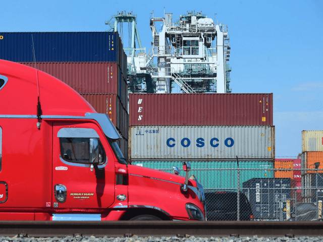 A container delivery truck passes containers stacked at the Port of Long Beach in Long Beach, California on July 6, 2018, including one from COSCO, the Chinese state-owned shipping and logistics company. - The twin ports of Long Beach and Los Angeles in Southern California are fearing a decline in …
