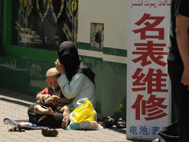 A Muslim ethnic Uighur woman begs with her baby on a street in Urumqi, capital of China's