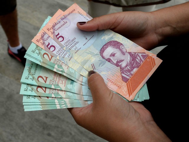 A woman holds new Bolivar-notes in downtown Caracas on August 21, 2018. - Caracas is issuing new banknotes after lopping five zeroes off the crippled bolivar, casting a pall of uncertainty over businesses and consumers across the country. (Photo by Federico PARRA / AFP) (Photo credit should read FEDERICO PARRA/AFP/Getty …