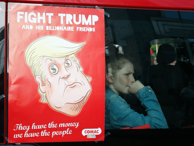 A girl sits in a van next to an anti-Donald Trump poster during a demonstration againt the US president in Brussels on May 24, 2017. US President Donald Trump is on a two-day visit to Belgium, to attend a NATO (North Atlantic Treaty Organization) summit on May 25. / AFP …