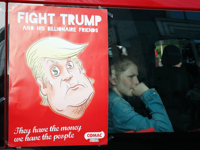 A girl sits in a van next to an anti-Donald Trump poster during a demonstration againt the