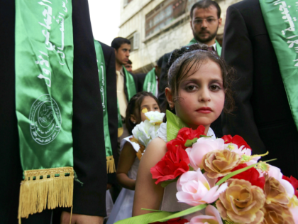 GAZA CITY, GAZA STRIP - AUGUST 05: A young relative stands with a groom during a mass wedd