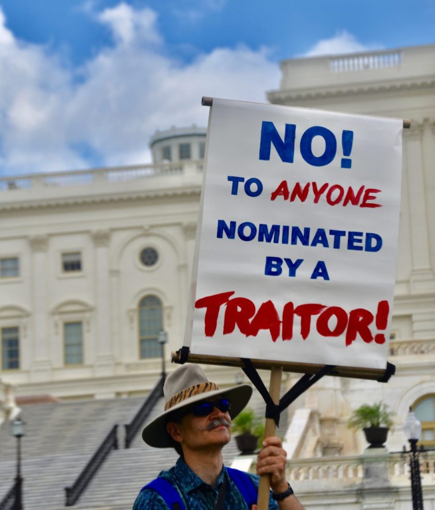 A protester at the anti-Kavanaugh rally on Wednesday on the grounds of the U.S. Capitol hold up a sign calling President Donald Trump a traitor. (Penny Starr/Breitbart News) 