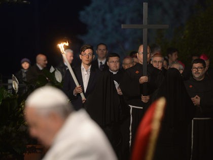 Penitents carry the cross next to Pope Francis during the Way of the Cross torchlight procession at the Colosseum on Good Friday on April 3, 2015 in Rome. Christians around the world are marking the Holy Week, commemorating the crucifixion of Jesus Christ, leading up to his resurrection on Easter. …
