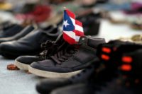 A Puerto Rican flag is placed on a pair of shoes among hundreds displayed in memory of those killed by Hurricane Maria in San Juan