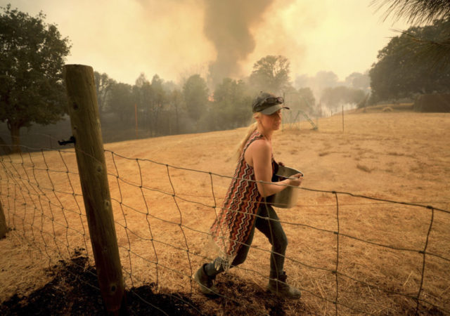California Wildfires Crystal Easter uses a pot of water to put out spot fires around her home, as her neighbor's home burns to the ground in the background, Monday, Aug. 6, 2018, in Spring Valley, Calif. The Ranch Fire spotted 200 yards across the valley, burning two homes in Spring Valley. (Kent Porter/The Press Democrat via AP) The Associated Press