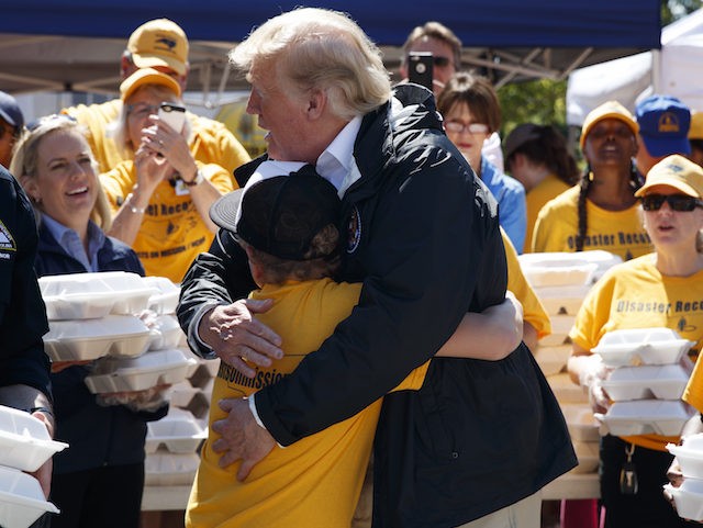 President Donald Trump hugs a young man while handing out prepackaged meals at Temple Baptist Church in an area impacted by Hurricane Florence, Wednesday, Sept. 19, 2018, in New Bern, N.C.