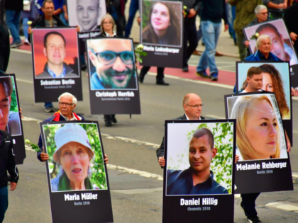 Demonstrators hold up placards showing portraits of victims of refugees during a protest o