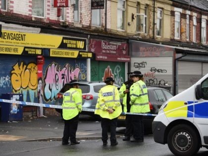 Police officers stand guard at the scene of a shooting at Claremont Road in the Moss Side
