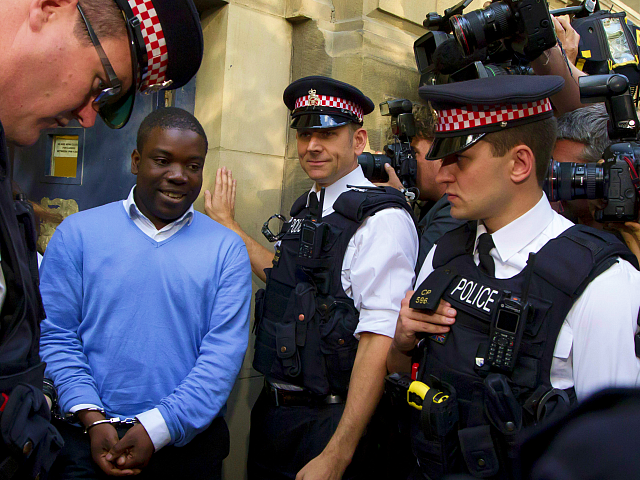 Alleged renegade UBS trader Kweku Adoboli, second from left, walks to be taken away in a security van flanked by police officers after appearing at the City of London Magistrates Court in London, Friday, Sept. 16, 2011. The alleged renegade trader accused of losing Swiss bank UBS about $2 billion …