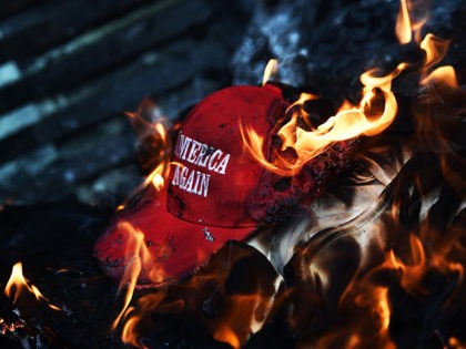 Anti-Trump demonstrator set a 'Make America Great Again' hat on fire in Washington, DC, on January 20, 2017. Masked, black-clad protesters carrying anarchist flags smashed windows and scuffled with riot police Friday in downtown Washington, blocks away from the route of the parade in honor of newly sworn-in President Donald …