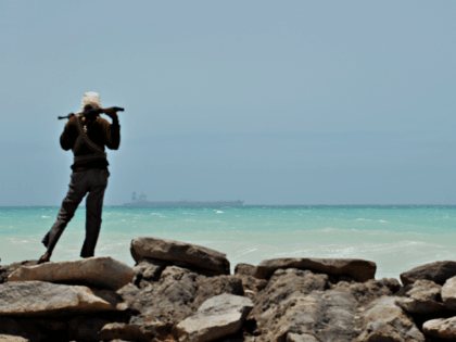 TO GO WITH AFP STORY BY JEAN-MARC MOJON A pirate stands on a rocky outcrop on the coast in Hobyo, central Somalia, on August 20, 2010 as he looks at a hijacked Korean supertanker anchored on the horizon. The Marshall Islands-flagged VLCC Samho Dream is a third of a kilometre …