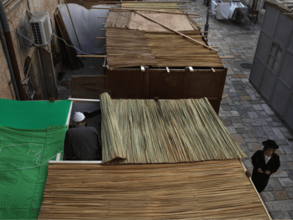 An ultra-Orthodox Jew walks between the Sukkahs (tabernacles) that fill a narrow street in