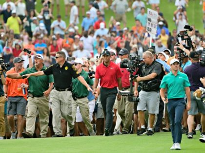 Tiger Woods, center, and Rory McIlroy, right, make their way down the 18th fairway during