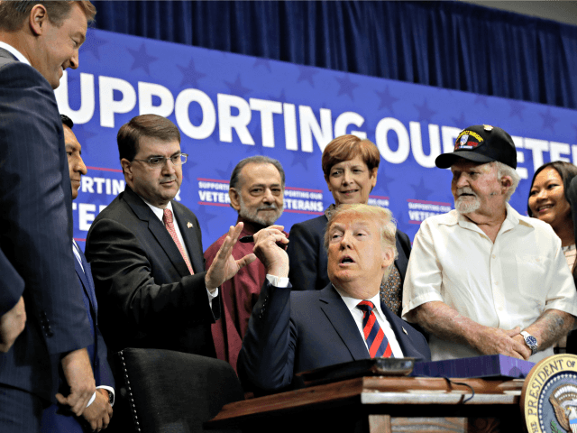 President Donald Trump hands a pen to Veterans Affairs Secretary Robert Wilkie during a sp
