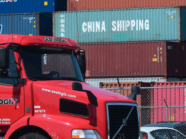 A container delivery truck drives past stacked piles of shipping containers at the Port of Long Beach in Long Beach, California on July 6, 2018, including one from China Shipping, a conglomerate under the direct administration of China's State Council. - The twin ports of Long Beach and Los Angeles …