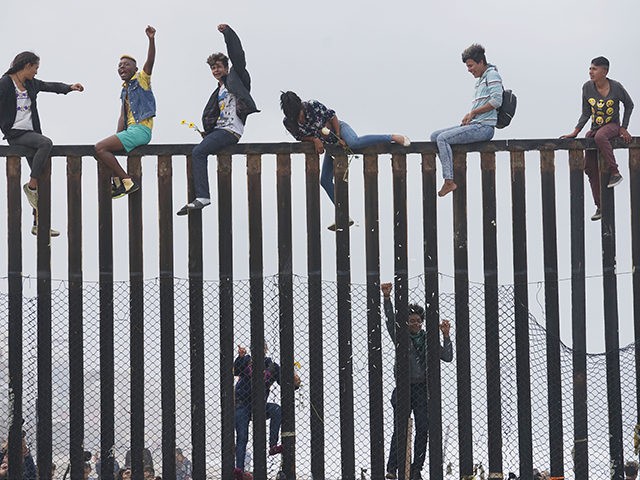 Migrant caravan demonstrators climb the US-Mexico border fence during a rally, on April 29, 2018, in San Ysidro, California. - The US has threatened to arrest around 100 Central American migrants if they try to sneak in from the US-Mexico border where they have gathered, prompting US President Donald Trump …