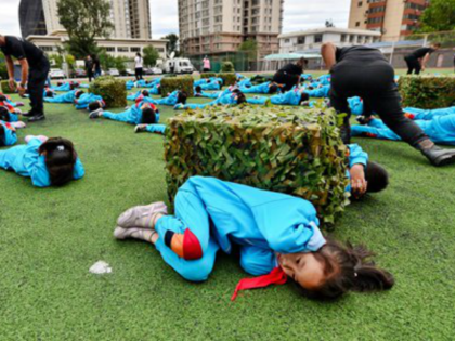 Students practice a protective stance Saturday during an air defense drill in Beijing. Pho