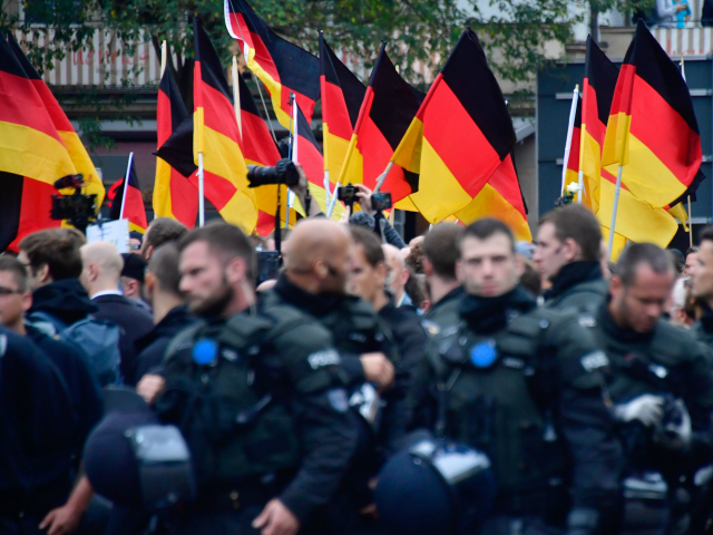 Supporters of the far-right Alternative for Germany (AfD) party wave German flags as they walk behind a barrage of riot police during a demonstration on September 1, 2018 in Chemnitz, eastern Germany. - The demonstration was organised in a reaction to a knife killing, allegedly by an Iraqi and a …